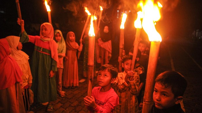 Sejumlah anak menyulut obor untuk mengikuti pawai di Komplek Grand Cinunuk Indah, Kabupaten Bandung, Jawa Barat, Rabu (12/5/2021). Pawai obor yang diselenggarakan oleh pengurus DKM Masjid setempat tersebut ditujukan untuk menyambut Idul Fitri 1442 H yang ditetapkan oleh pemerintah pada Kamis (13/5/2021). ANTARA FOTO/Raisan Al Farisi/foc.