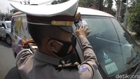 Petugas Kepolisian menempelkan stiker larangan mudik pada kendaraan yang telah diperiksa di perbatasan Jawa Tengah dan D.I. Yogyakarta.   