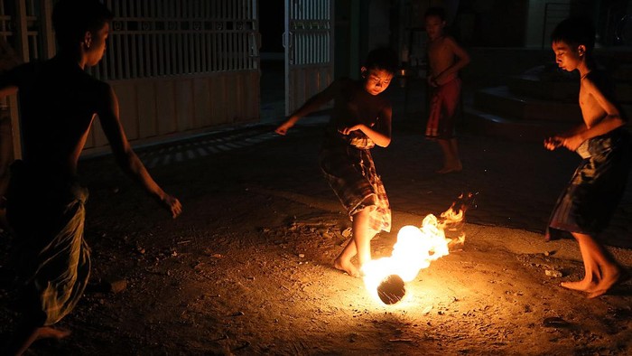 Sejumlah remaja masjid bermain sepakbola api di halaman Masjid Batul Fatah Gedog, Blitar, Jawa Timur, Selasa (11/5/2021). Tradisi sepakbola api yang dimainkan jelang pelaksanaan ibadah sahur pada malam terakhir bulan Ramadhan tersebut merupakan wujud rasa syukur masyarakat sekitar karena dapat menjalankan ibadah puasa hingga dipenghujung bulan Ramadhan. ANTARA FOTO/Irfan Anshori/nz