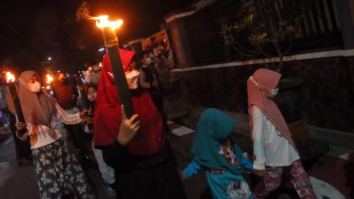 Sejumlah santri TPQ Pesantren Miftahul Huda membawa obor sambil bertakbir berkeliling desa di Blitar, Jawa Timur, Rabu (12/5/2021) malam. Tradisi takbiran keliling yang dilakukan dengan penerapan ptotokol kesehatan ketat guna menghindari penularan COVID-19 tersebut guna menyambut hari raya Idul Fitri 1442 H . ANTARA FOTO/Irfan Anshori/foc.