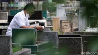 Seorang warga berdoa di makam keluarganya.