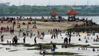 Para wisatawan bermain di sepanjang pantai.