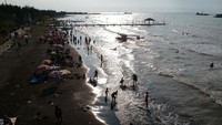Foto udara pengunjung bermain air di pinggir pantai di Obyek Wisata Pantai Alam Indah, Tegal, Jawa Tengah, Jumat (14/5/2021). ANTARA FOTO/Oky Lukmansyah.