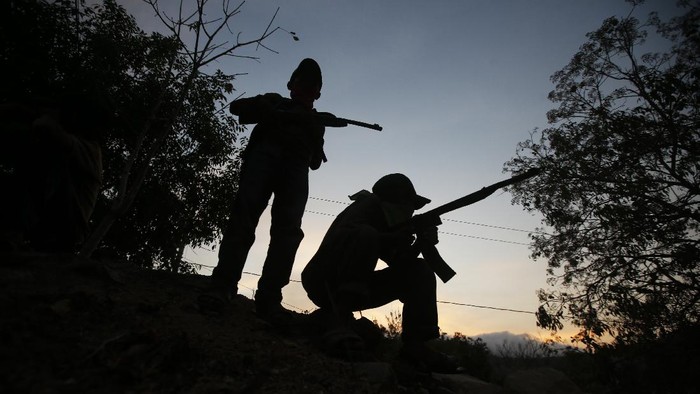 Community policeman Silvano Martinez guards his 11-year-old nephew Geovanni Martinez as he observes his goats in a pasture outside Ayahualtempa, a town in Guerrero state where residents provide security from the violence of rivaling gangs in Mexico, Wednesday, April 28, 2021. The 11-year-old said he yearns to return to school, closed for the past year by the pandemic, and when asked if he would shoot at an enemy he issued a convincing 