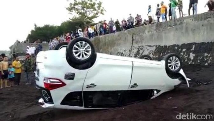 Sebuah mobil wisatawan di Banyuwangi nyungsep hingga terbalik di pinggir Pantai Blimbingsari. Sebelum nyungsep, mobil tersebut menabrak dua motor yang parkir.