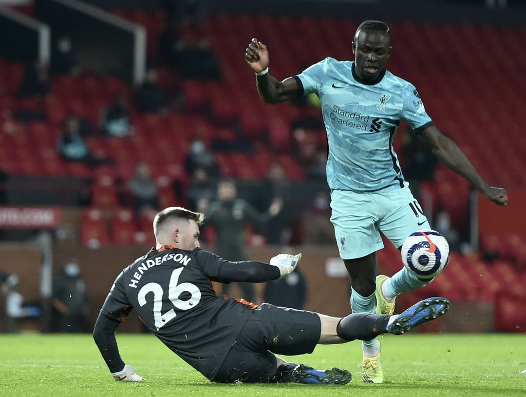 Manchester United's goalkeeper Dean Henderson, left, makes a save in front of Liverpool's Sadio Mane during the English Premier League soccer match between Manchester United and Liverpool, at the Old Trafford stadium in Manchester, England, Thursday, May 13, 2021. (Peter Powell/Pool via AP)