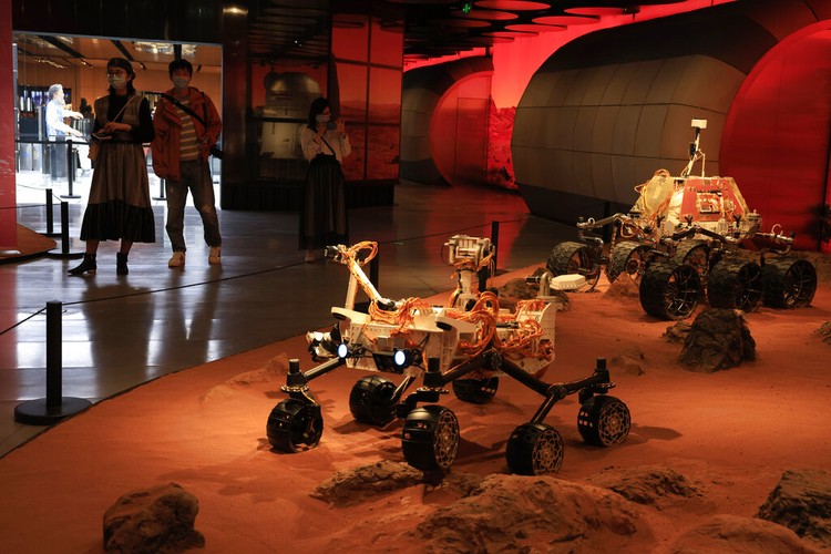 China Space Mars Mission Visitors pass by an exhibition depicting rovers on Mars in Beijing on Friday, May 14, 2021. China says its Mars probe and accompanying rover are to land on the red planet sometime between early Saturday morning and Wednesday Beijing time. (AP Photo/Ng Han Guan)