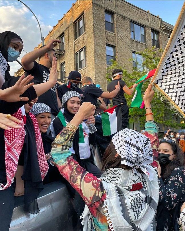 Dalam beberapa foto, ia terlihat membawa bendera Palestina dan menyuarakan protesnya. Tak tampil glamour seperti yang biasa ditunjukkannya saat bekerja, Bella pun memilih menggunakan atasan bernuansa tradisional dan Keffiyeh saat turun berdemo ke jalan. Foto: Instagram @bellahadid