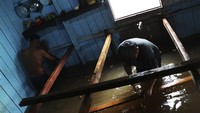 Saat sungai terus naik, suara gergaji listrik di Anama terus terdengar saat penduduk memotong papan dan balok untuk membangun penopang barang-barang di rumah mereka agar terhindar dari banjir.