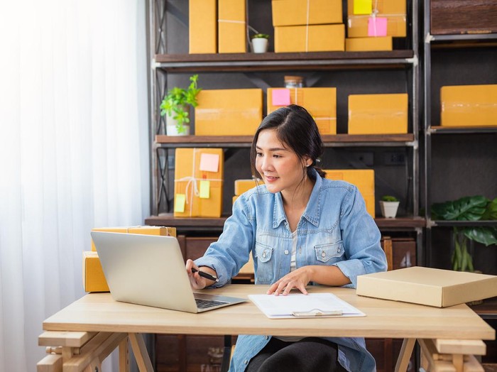 Young Asian female freelancer using her laptop and working at home, Small business female owner or Start up small business entrepreneur working online marketing packaging box delivery