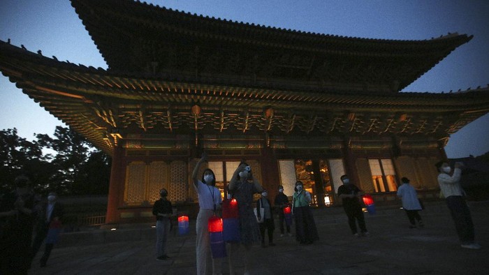 Jelajah Kemegahan Istana Changdeokgung di Korea Selatan Visitors holding Korean traditional lanterns walk around during a Moonlight Tour amid the coronavirus pandemic at Changdeokgung Palace in Seoul, South Korea, Thursday, May 13, 2021. (AP Photo/Ahn Young-joon)
