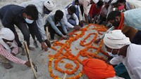 Keluarga berdoa setelah menguburkan jenazah di kuburan pasir dangkal di tepi sungai Gangga di Prayagraj, 16 Mei 2021.