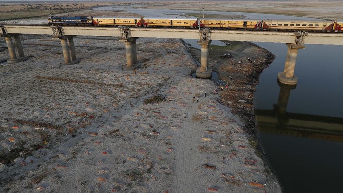 Potret Ratusan Mayat Terkubur di Tepi Sungai Gangga Bodies of suspected Covid-19 victims are seen in shallow graves buried in the sand near a cremation ground on the banks of Ganges River in Prayagraj, India, Saturday, May 15, 2021. (AP Photo/Rajesh Kumar Singh)