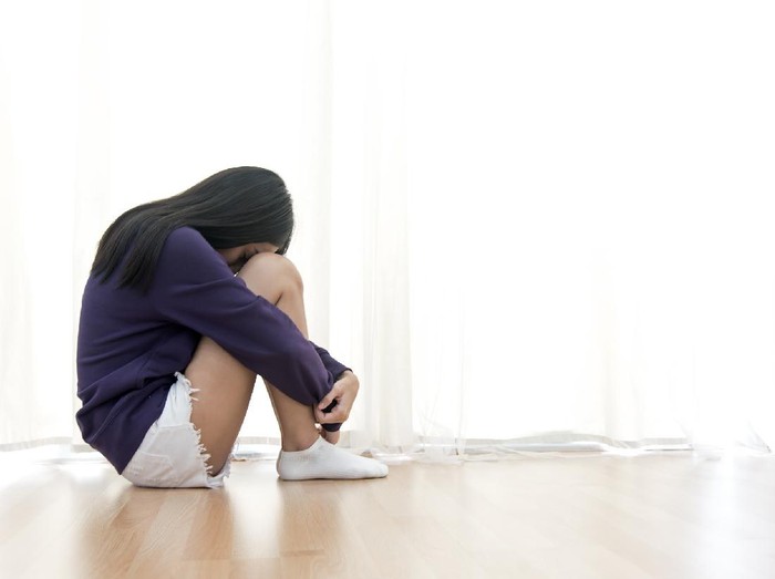 687411216 Sad young woman sit in her room and covering her face