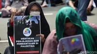 Massa membawa poster bertuliskan Hentikan Penjajahan dan Pembantaian di Palestina.