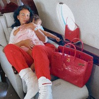 Berikut potret kebersamaan Georgina Rodriguez bersama anaknya saat naik private jet. Kali ini wanita yang disebut sebagai salah satu selebgram berbayar termahal di kalangan para WAGs itu tampak membawa tas Hermes merah andalannya. Foto: Instagram @georginagio