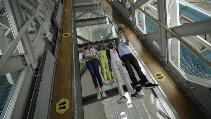 A visitor walks over the glass walkway at the Tower Bridge Visitor Attraction, in London, on the first day it was allowed to reopen as the British government relaxes its third coronavirus lockdown restrictions, Monday, May 17, 2021. (AP Photo/Matt Dunham)