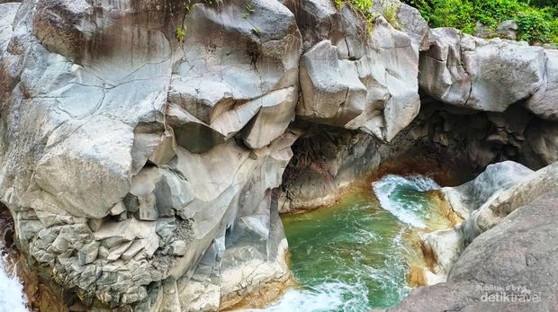 Air berwarna kehijauan mengalir di antara batuan berwarna putih