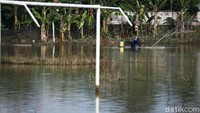 Warga tampak sibuk menjala ikan di tengah lapangan yang terendam banjir.