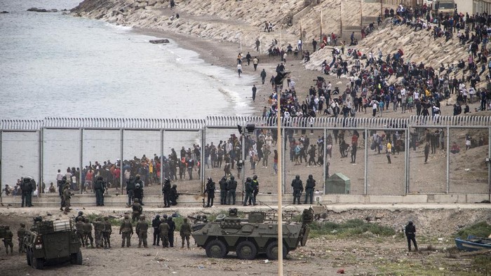 Ribuan Migran Maroko Berenang ke Spanyol A Guardia Civil officer rescues people from the water who try to arrive into the Spanish territory next to the border of Morocco and Spain, at the Spanish enclave of Ceuta, on Tuesday, May 18, 2021. Ceuta, a Spanish city of 85,000 in northern Africa, faces a humanitarian crisis after thousands of Moroccans took advantage of relaxed border control in their country to swim or paddle in inflatable boats into European soil. Around 6,000 people had crossed by Tuesday morning since the first arrivals began in the early hours of Monday, including 1,500 who are presumed to be teenagers. (AP Photo/Javier Fergo)