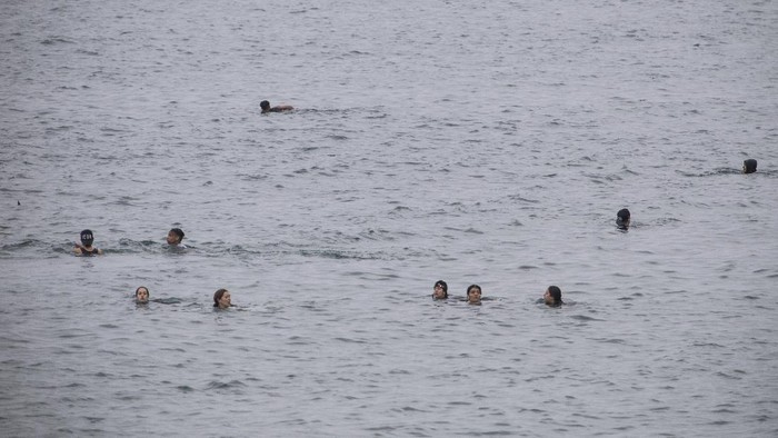 A Guardia Civil officer rescues people from the water who try to arrive into the Spanish territory next to the border of Morocco and Spain, at the Spanish enclave of Ceuta, on Tuesday, May 18, 2021. Ceuta, a Spanish city of 85,000 in northern Africa, faces a humanitarian crisis after thousands of Moroccans took advantage of relaxed border control in their country to swim or paddle in inflatable boats into European soil. Around 6,000 people had crossed by Tuesday morning since the first arrivals began in the early hours of Monday, including 1,500 who are presumed to be teenagers. (AP Photo/Javier Fergo)