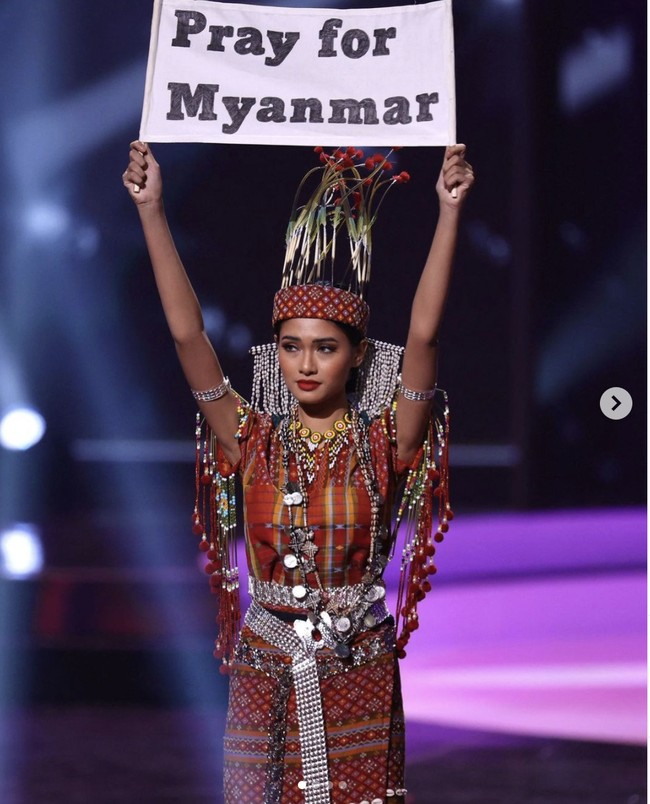 Candy Thuzar atau Thuzar Wint Lwin memeragakan kostum nasionalnya yang merupakan busana tradisional suku Chi di Myanmar dengan membawa kertas bertuliskan, Pray for Myanmar.” Saat ini memang  Myanmar memang belum sepenuhnya pulih dari konflik internal menyusul kudeta militer.  Foto: Dok. Instagram @thuzar_wintlwin