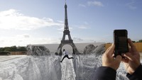 Seorang pria melompat di atas karya seni dengan latar belakang Menana Eiffel di alun-alun Trocadero, Paris, Prancis, Rabu (19/5/2021) waktu setempat.  