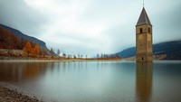 Seperti ini penampakan danau Resia saat terendam air, hanya menyisakan menara gereja dari abad ke-14. Pemandangan yang cukup mengerikan ini jadi inspirasi serial Netflix dan jadi destinasi yang cukup populer di kalangan traveler. (Getty Images/iStockphoto/Marco_Piunti)