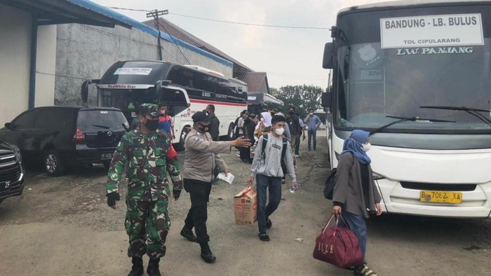 Petugas mengarahkan pemudik yang baru tiba di pool bus Ciputat, Tangsel untuk diswab antigen