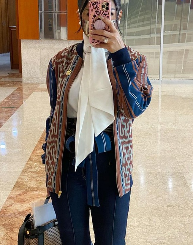 Kain tenun bisa dijadikan pakaian yang modern. KD menyulap kain tenun menjadi potongan jaket bomber. Agar tetap terlihat profesional, ia memadankannya dengan kemeja dengan aksen pita di bagian leher.  Foto: dok. Instagram/@krisdayantilemos
