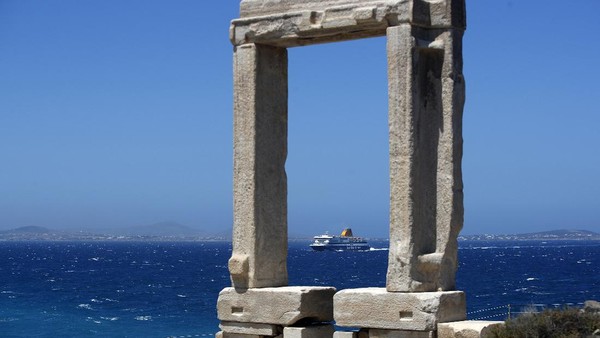 Kapal feri mendekati Pelabuan Portara, terlihat dari gapura marmer yang menjadi reruntuhan Kuil Apollo pada 530 SM, di Pulau Aegean, Yunani. AP Photo/Thanassis Stavrakis  
