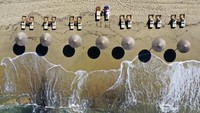 Seorang wanita menikmati matahari di pantai Plaka di pulau Aegean Naxos, Yunani. AP Photo/Thanassis Stavrakis  