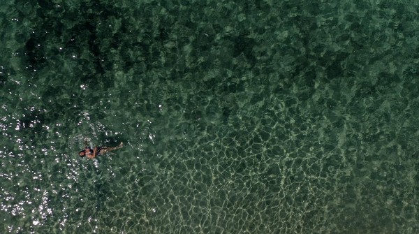 Seorang wanita berenang di Pantai Agios Prokopios di Pulau Aegean, Yunani. Dikutip dari Reuters, Menteri Pariwisata Yunani, Haris Theoharis, mengatakan mereka telah membuka industri pariwisata kepada dunia. AP Photo/Thanassis Stavrakis  