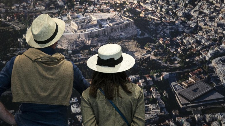Pesona Pantai Yunani yang Sudah Dibuka Lagi Untuk Turis Dunia Visitors look at an aerial photograph of Athens inside the Acropolis museum, in Athens, Friday, May 14, 2021. Tourism services and museums reopened on Friday, while a nightly curfew shortened by another 90 minutes, as authorities relaxed restrictions for the tourism season. (AP Photo/Yorgos Karahalis)