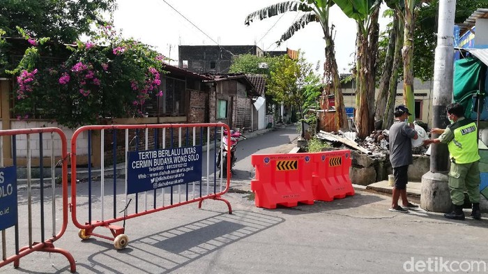 Petugas berjaga di wilayah isolasi di kampung yang satu kelurahan dengan rumah Presiden Jokowi di Sumber, Banjarsari, Solo, Kamis (20/5/2021).
