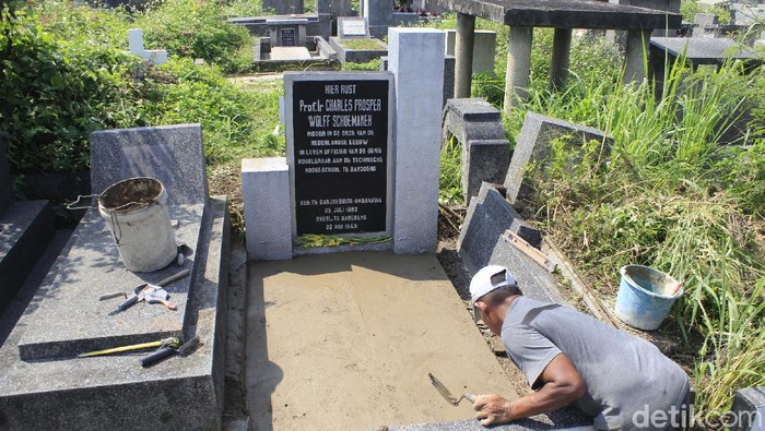 Seorang tukang tengah memperbaiki makam C.P Wolff Schoemaker