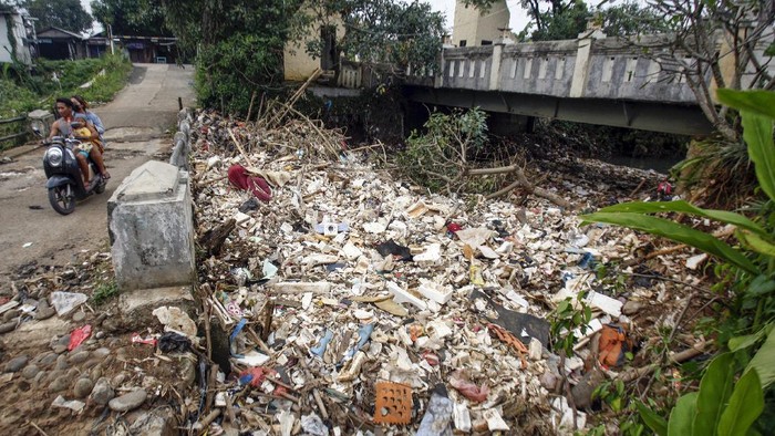 Warga melintas jembatan sungai Kali Baru yang tersumbat sampah, Cilebut, Kabupaten Bogor, Jawa Barat, Kamis (20/5/2021). Tersumbatnya sungai oleh sampah tersebut dikeluhkan oleh warga sekitar karena menjadi salah satu penyebab banjir di daerah tersebut. ANTARA FOTO/Yulius Satria Wijaya/foc.