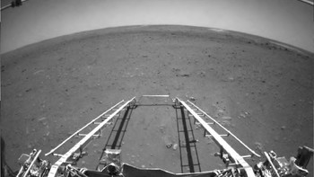 Foto hitam putih ini diambil menggunakan kamera penghindar rintangan di bagian depan rover. Foto dengan lensa wide-angle ini memperlihatkan bagaimana wahana pendarat atau lander mengeluarkan jalur untuk membantu Zhurong menjejaki permukaan Mars untuk pertama kalinya. (Foto: CNSA)