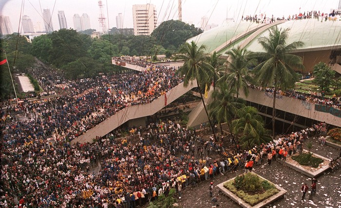 Indonesian students throw streamers from a rooftop over a crowd gathered in front of the Split Dome of the Assembly Hall of Parliament in Jakarta 20 May. Thousands rallied at the parliament while security forces maintained tight controls on the streets leading to the presidential palace and on the capitals main avenues. AFP PHOTO/KEMAL JUFRI (Photo by KEMAL JUFRI / AFP)