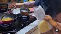 Paling suka makan mie, begini kehebohan Ria saat tengah memasak bumbu lengkap dengan mie di tangannya. Kira-kira Ria mau masak apa ya? Foto: Rumah Ria Ricis