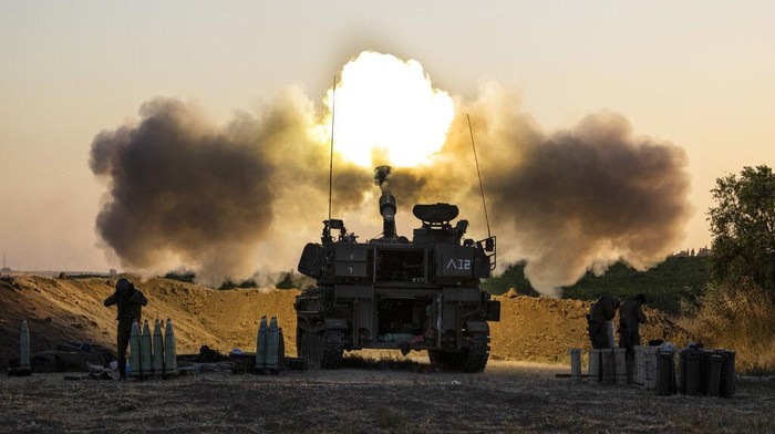 A Israeli soldier takes cover as an Iron Dome air defense system launches to intercept a rocket from the Gaza Strip, in Ashkelon, southern Israel, Tuesday, May 11, 2021. (AP Photo/Ariel Schalit)