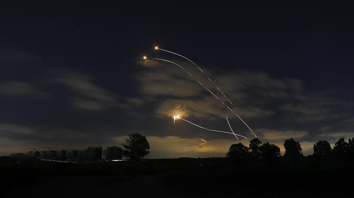A Israeli soldier takes cover as an Iron Dome air defense system launches to intercept a rocket from the Gaza Strip, in Ashkelon, southern Israel, Tuesday, May 11, 2021. (AP Photo/Ariel Schalit)