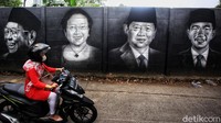 Seorang warga melintas di samping dinding yang dihiasi mural bergambar wajah para presiden Indonesia.  