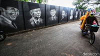 Seorang warga melintas di depan dinding yang dihiasi mural wajah para presiden Indonesia di Cipondoh, Kota Tangerang, Jumat (21/5/2021).