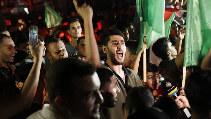 Sorak-sorai Warga Gaza Sambut Gencatan Senjata Hamas-Israel Palestinians wave green Hamas flags while celebrating the cease-fire agreement between Israel and Hamas in Gaza City, early Friday, May 21, 2021. (AP Photo/Adel Hana)