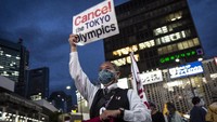 Seorang pengunjuk rasa memegang plakat saat melakukan protes menentang Olimpiade Tokyo di Tokyo, Jepang. 