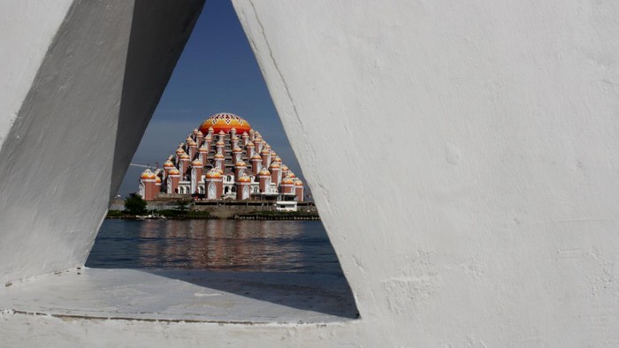 Nelayan melintas menggunakan perahu di perairan Pantai Losari dengan latar belakang Masjid 99 Kubah di Makassar, Sulawesi Selatan, Sabtu (22/5/2021). Pembangunan masjid yang diharapkan menjadi ikon baru Kota Makassar tersebut telah memasuki tahap tiga yang ditargetkan rampung pada 2022 dengan anggaran yang masih dibutuhkan sebesar Rp72 miliar. ANTARA FOTO/Arnas Padda/yu/foc.