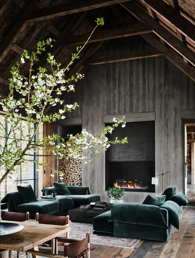 Kayu-kayuan berwarna hitam mendominasi interior rumah. Di ruang keluarga yang dilengkapi perapian, terdapat sebuah sofa lounge hijau berbahan beludu yang mempertegas aura kemewahan rumah tersebut. Foto: Dok. Architectural Digest/Douglas Friedman