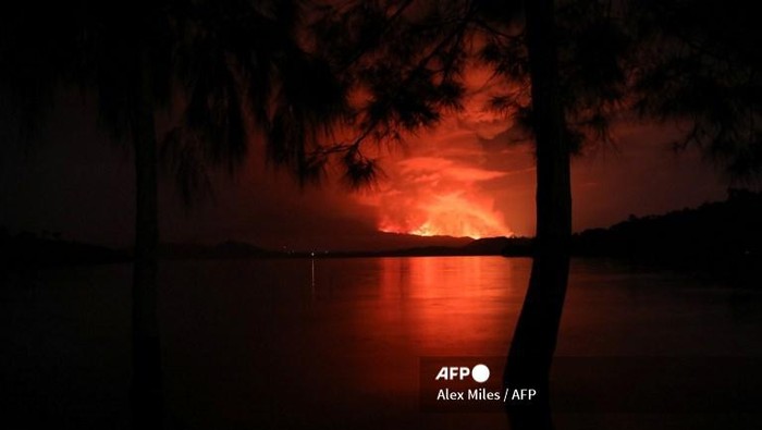 This general view taken on May 22, 2021 from Tchegera Island outsoide Goma on the lake Kivu in the East of the Democratic Republic of Congo shows flame spewing from the Nyiragongo volcano. - The famous Nyiragongo volcano, near the city of Goma, in the east of the Democratic Republic of the Congo (DRC), suddenly became active on Saturday evening, an AFP correspondent noted. Strong emanations of glowing light coming out of the crater were visible from Goma, while a smell of sulfur was perceptible in the city, located on the southern flank of the volcano, on the shores of Lake Kivu, he noted. (Photo by Alex Miles / AFP)