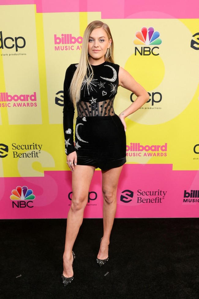 Presenter Kelsea Ballerini memilih tampilan simpel dengan gaun ketat hitam beraksen bintang-bintang dan motif hati. Busana ini keluaran desainer Nedret Taciroglu. Foto: Rich Fury / GETTY IMAGES NORTH AMERICA / Getty Images via AFP